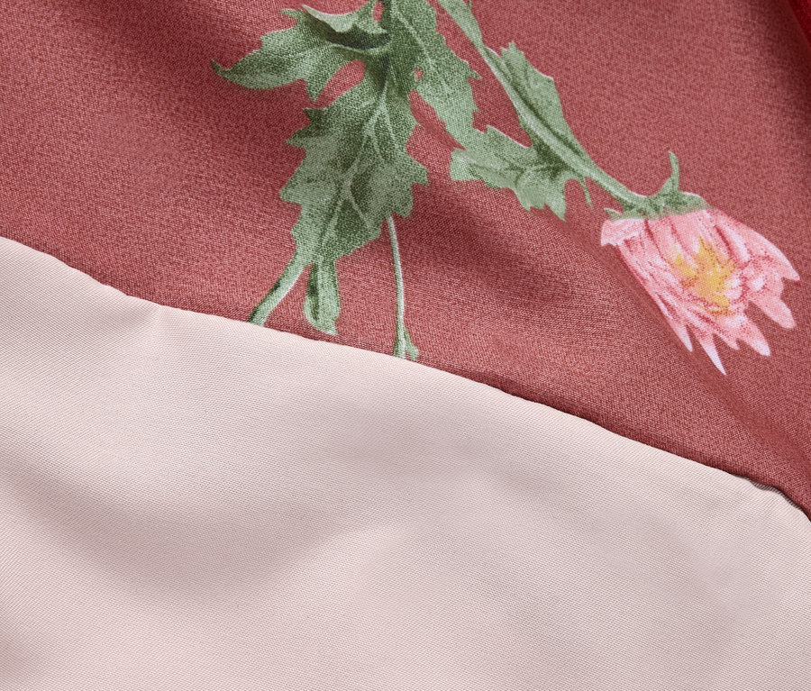 Détail d'un tissu rose avec un motif floral et une bordure crème.