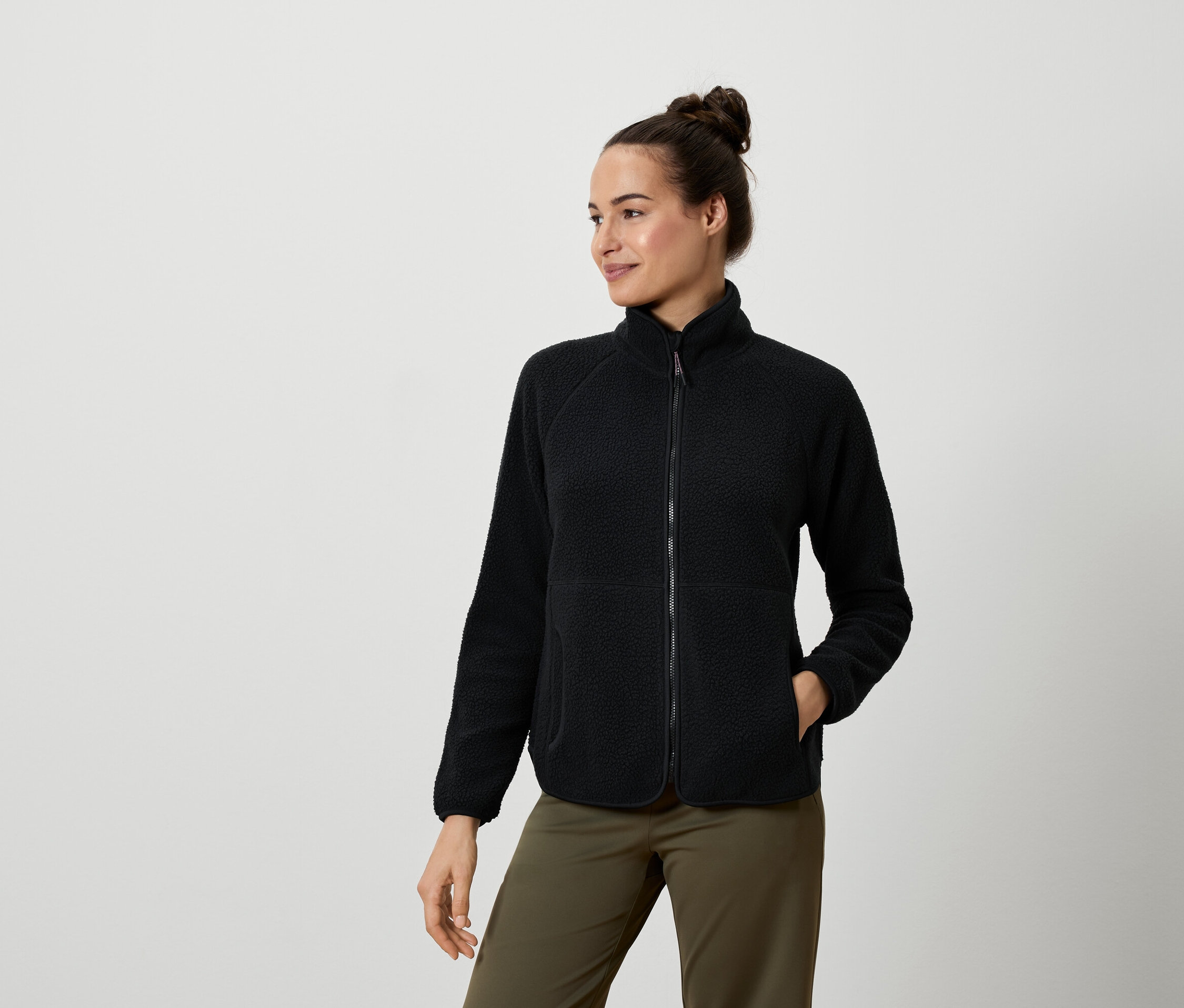 Femme portant une veste en polaire noire et un pantalon vert olive.