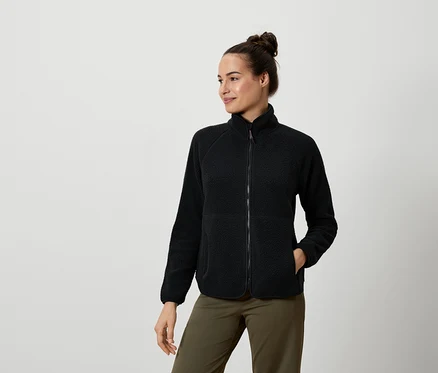 Femme portant une veste en polaire noire et un pantalon vert olive.