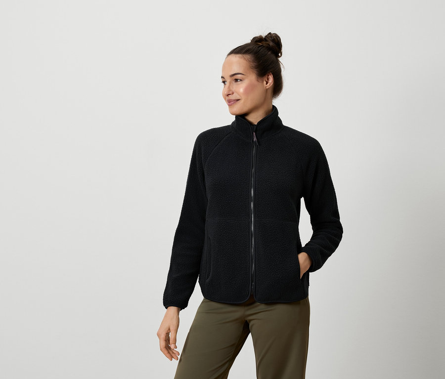 Femme portant une veste en polaire noire et un pantalon vert olive.