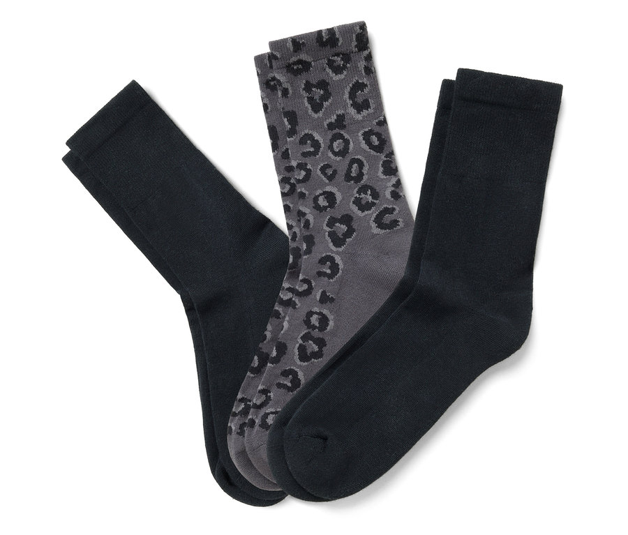 Trois paires de chaussettes, noires et grises, sont posées sur un fond blanc.