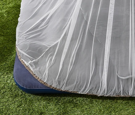 Une moustiquaire de voyage sur un matelas dans l'herbe.