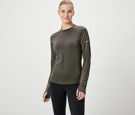 Une femme porte un t-shirt à manches longues vert olive et un legging noir.