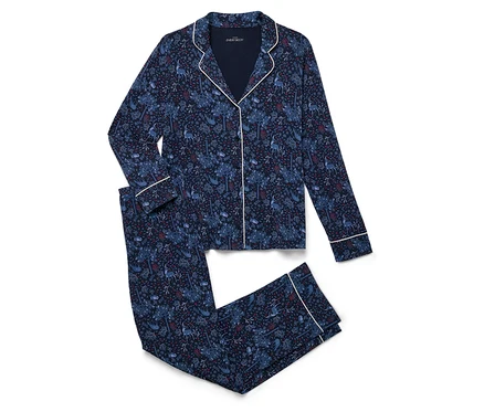 Un ensemble de pyjama bleu marine avec imprimé intégral est plié sur un fond blanc.