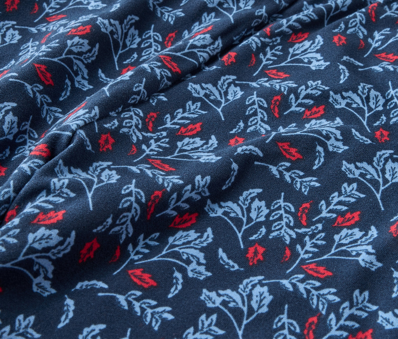 Gros plan d'un tissu bleu foncé avec un imprimé de feuilles rouges et bleu clair.