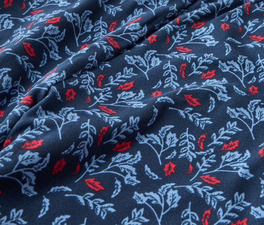Gros plan d'un tissu bleu foncé avec un imprimé de feuilles rouges et bleu clair.