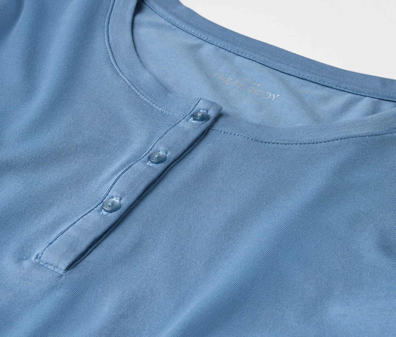 Gros plan d'un t-shirt bleu clair avec des boutons.