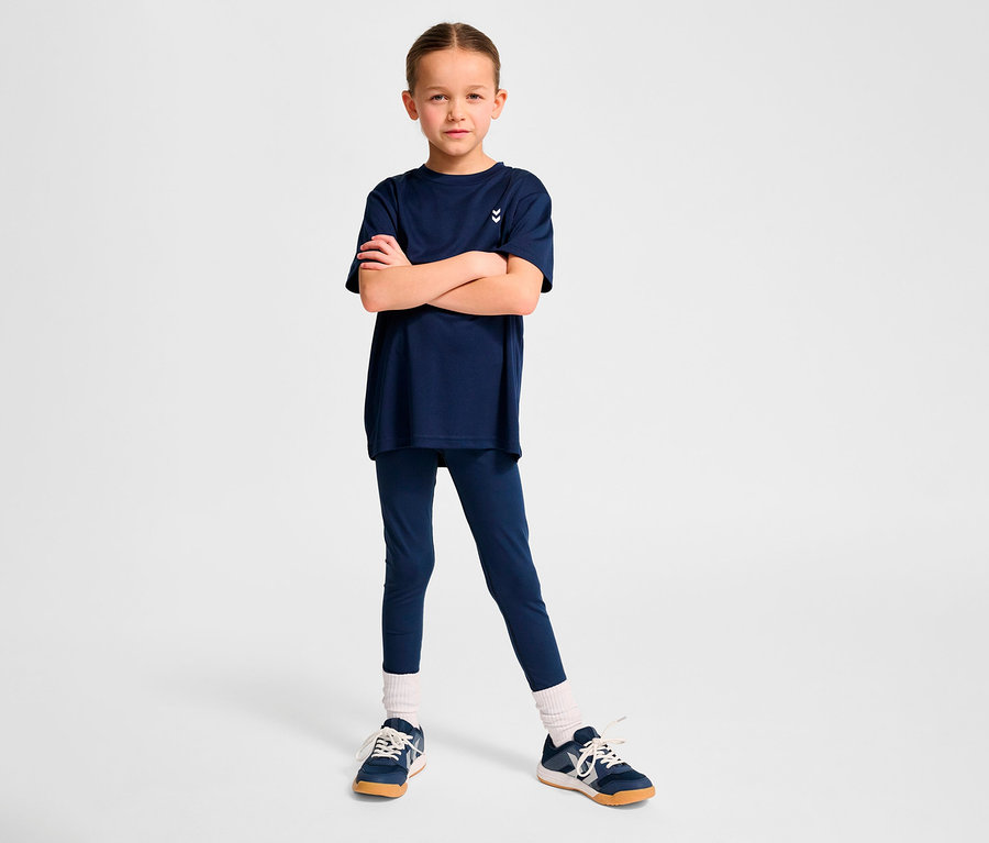 Fillette posant en T-shirt d’entraînement HUMMEL HMLJR pulse bleu foncé et leggings.