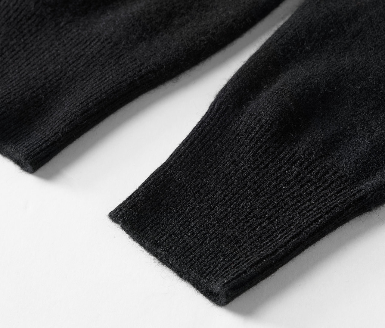 Gros plan sur la manche tricotée noire d'un pull.