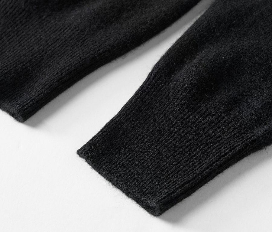 Gros plan sur la manche tricotée noire d'un pull.