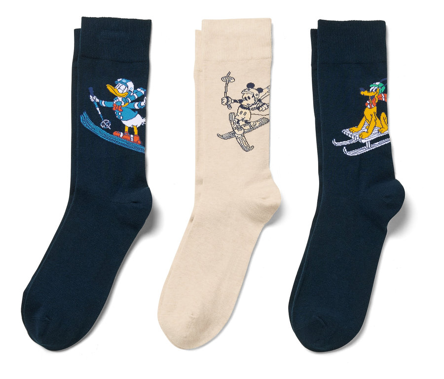 Trois paires de chaussettes avec des personnages de dessins animés faisant du ski sur fond blanc.