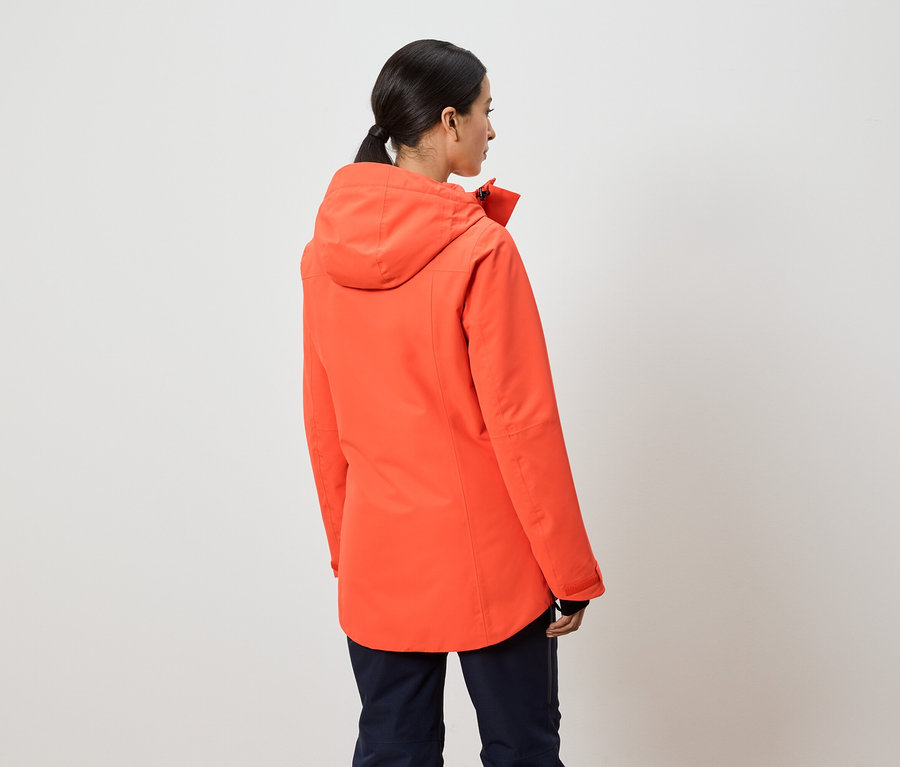 Une femme, dos à la caméra, porte une veste orange à capuche.