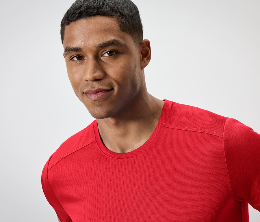 Portrait d'un homme aux cheveux courts portant un t-shirt rouge.