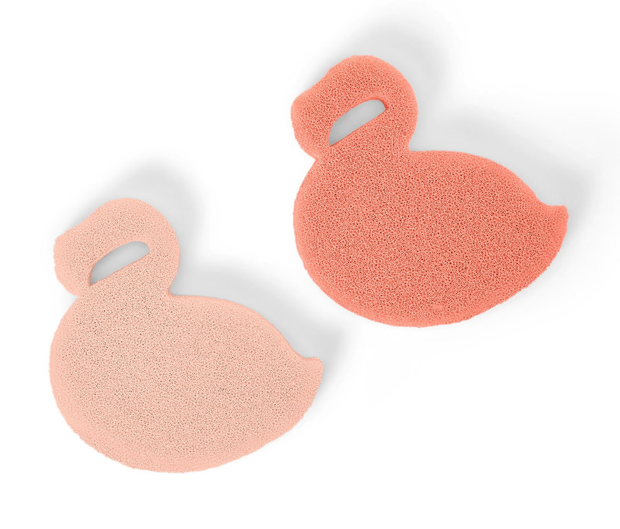 Deux éponges en silicone en forme de cygne, une rose clair et une rose corail, sont posées sur un fond blanc.
