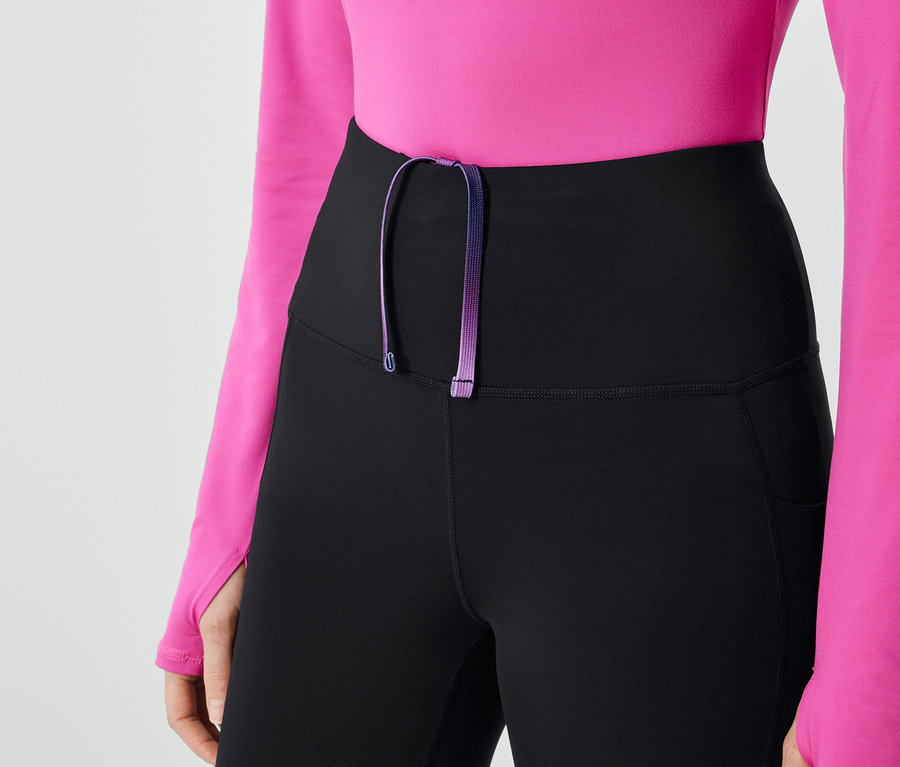 Gros plan d'un legging noir pour femme avec cordon de serrage violet et haut rose.