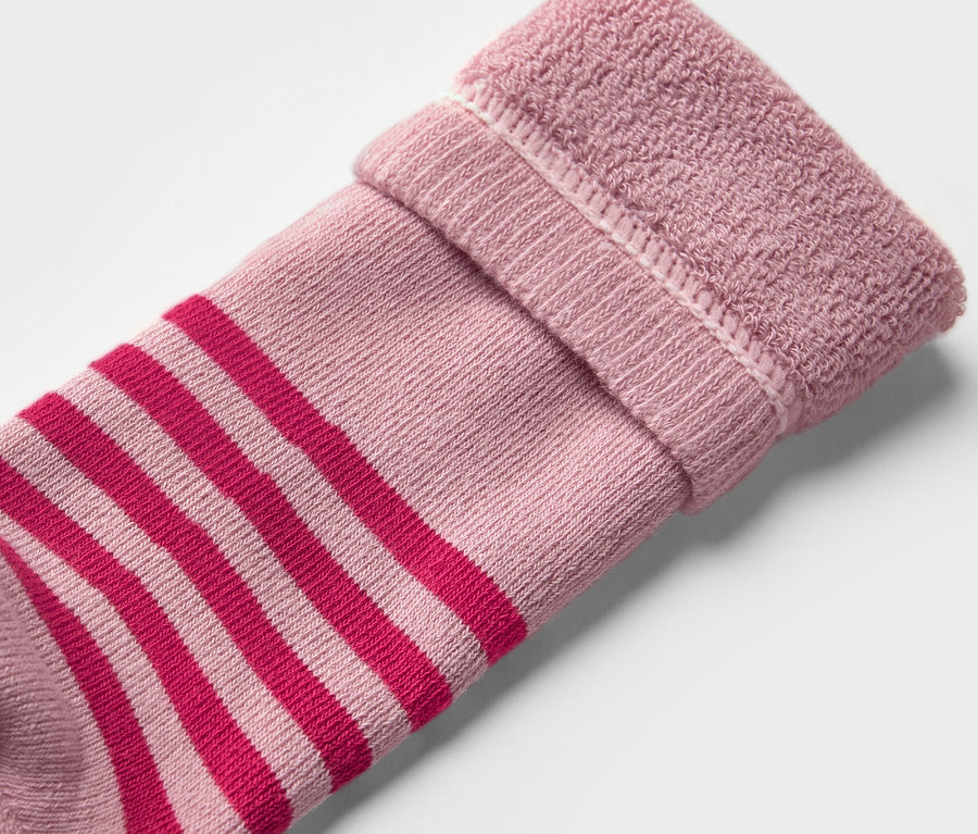 Gros plan sur une chaussette pour bottes en caoutchouc pour enfants (2 paires, à fleurs). La chaussette est rose avec des rayures rouges et un bord replié.