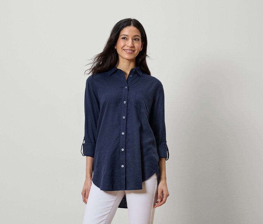 Femme portant une chemise bleu marine et un pantalon blanc.