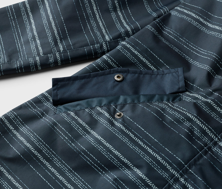 Gros plan sur une veste bleu marine à rayures blanches avec une poche à deux boutons-pression.