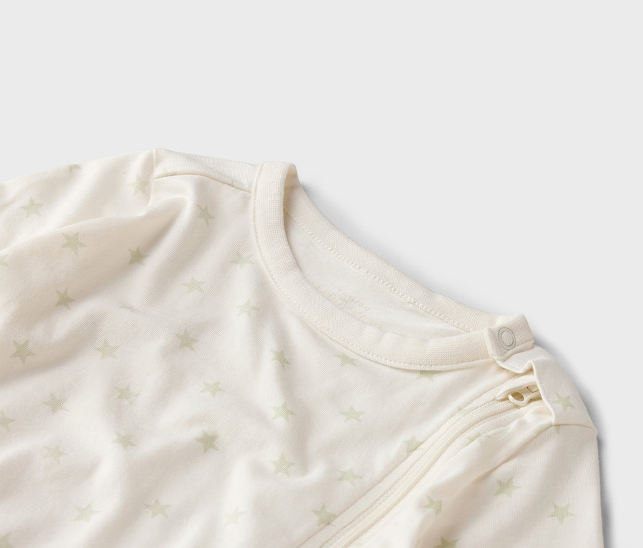 Gros plan d'une gigoteuse claire pour bébé avec un motif d'étoiles, une fermeture éclair et un bouton au niveau du cou.