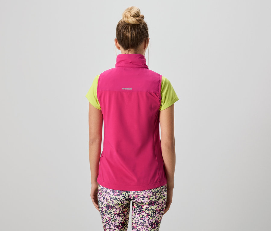 Vue de dos d'une femme avec un chignon portant un gilet rose sur un t-shirt vert clair et un legging à motif floral.