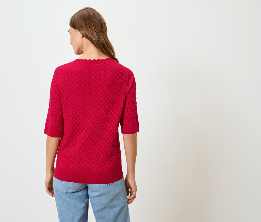 Vue arrière d'une femme aux longs cheveux bruns portant un pull rouge et un jean bleu.