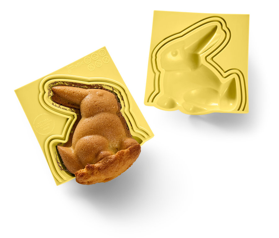 Un lapin cuit dans un moule jaune à côté d'un moule à lapin jaune vide.