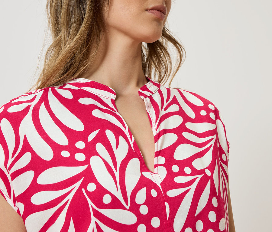 Haut du corps d'une femme portant une robe à motifs rouge et blanc.
