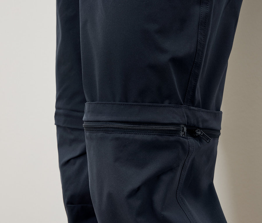 Gros plan d'un pantalon bleu marine avec une poche zippée sur la jambe.