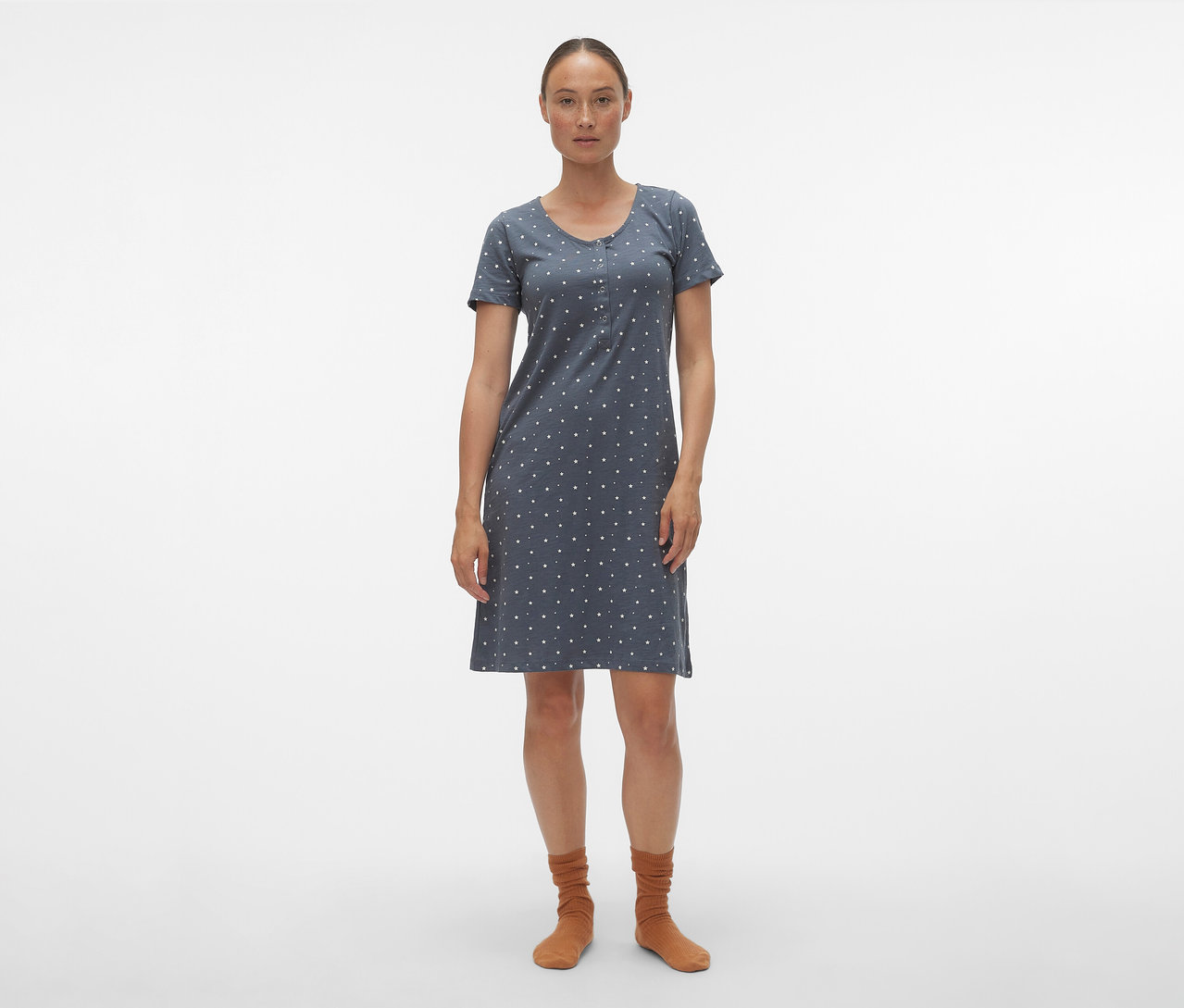 Une femme porte une chemise de nuit bleue MAMALICIOUS « MLMIRA » à pois blancs et des chaussettes marron sur fond blanc.