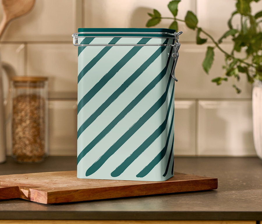 Une boîte à café rayée est posée sur une planche à découper en bois.