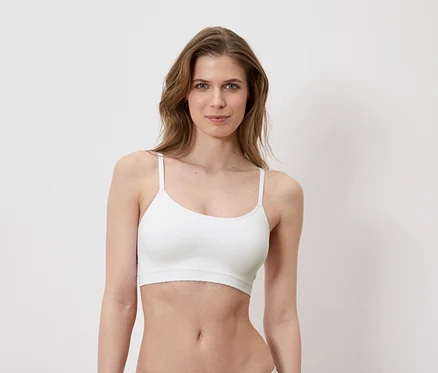 Une femme porte un soutien-gorge de sport blanc sur un fond blanc.