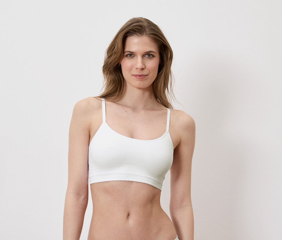 Une femme porte un soutien-gorge de sport blanc sur un fond blanc.