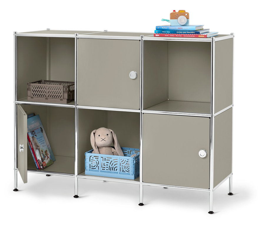 Étagère modulable grise à six compartiments, dont trois avec portes, remplie d'un appareil photo jouet, de livres, d'un panier, d'un lapin en peluche et d'un livre pour enfants.