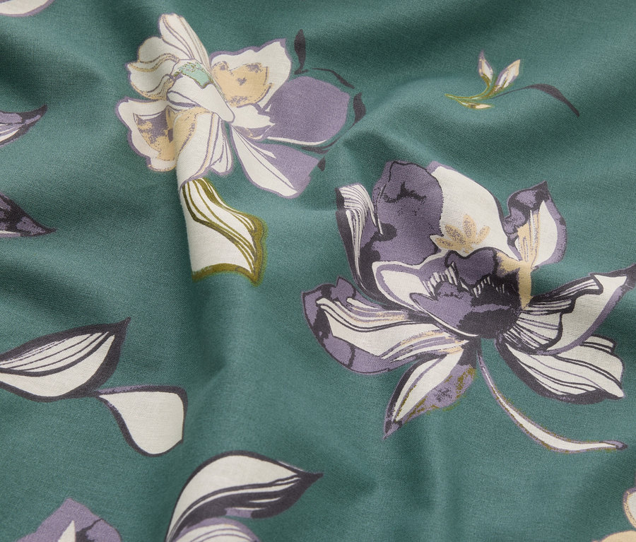 Gros plan d'un tissu à motifs floraux dans des tons de vert, violet et crème.