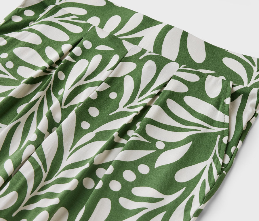 Gros plan d'un pantalon avec un motif de feuilles vertes et blanches.
