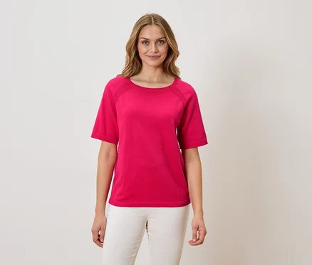 Femme portant un t-shirt rose et un pantalon blanc.