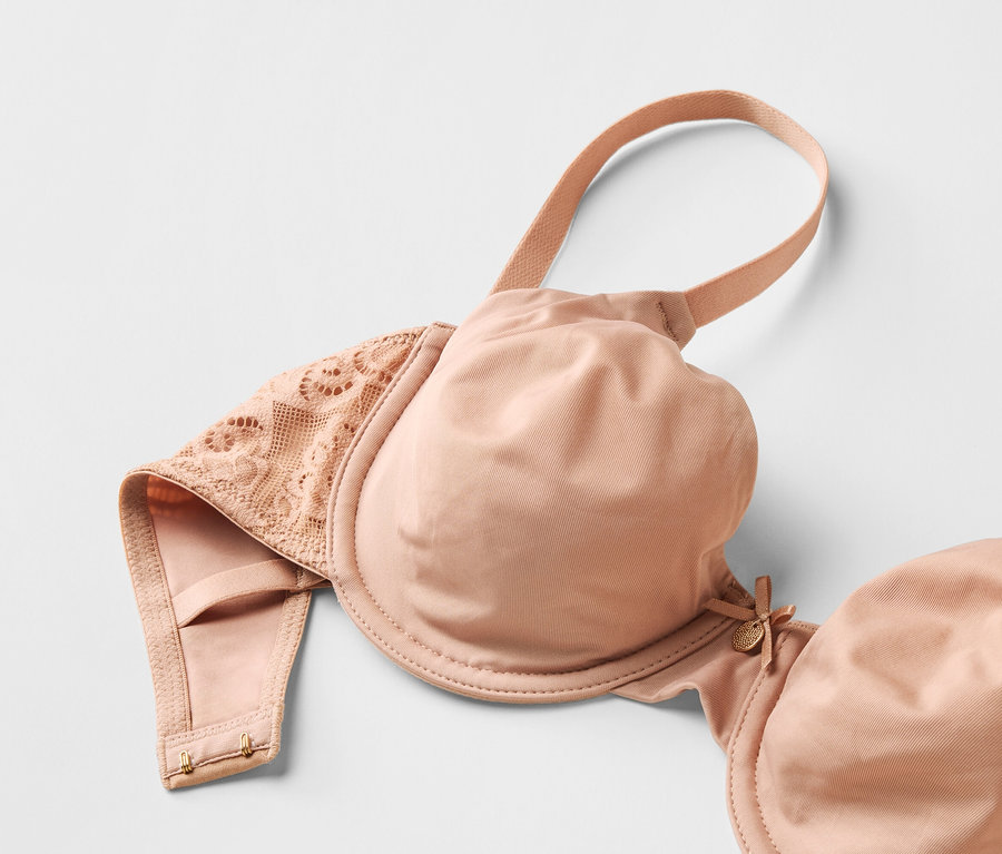 Gros plan d'un soutien-gorge beige avec de la dentelle sur fond blanc.