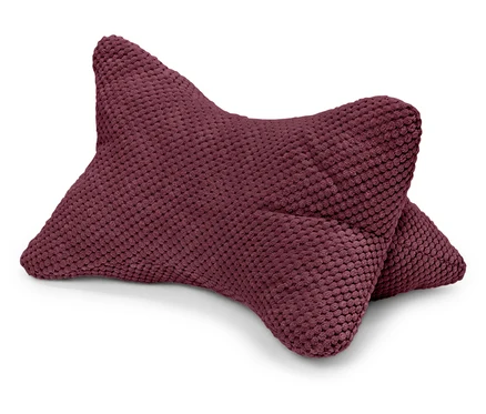 Un coussin bordeaux texturé est posé sur un fond blanc.
