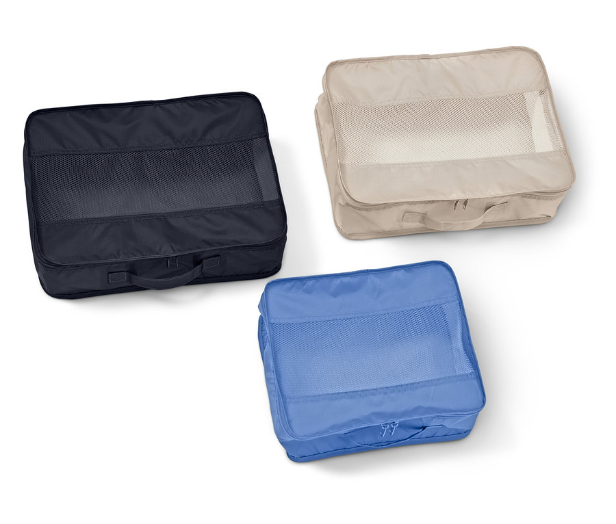Trois organisateurs de valise rectangulaires avec fenêtres en maille en bleu marine, beige et bleu sont posés sur un fond blanc.