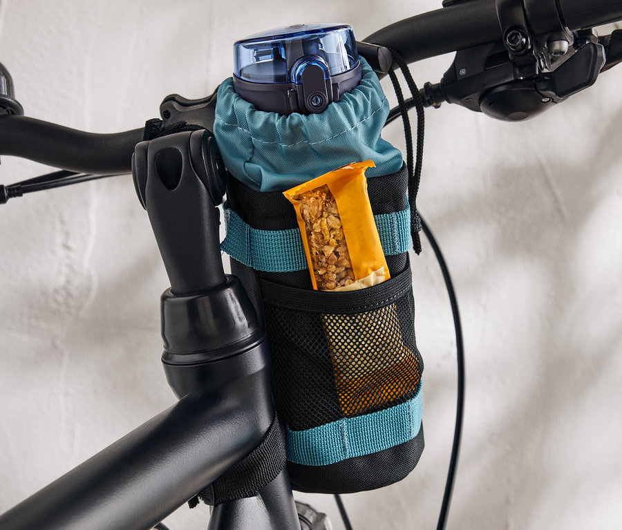 Une gourde bleue et une barre de céréales sont placées dans un support fixé au vélo.