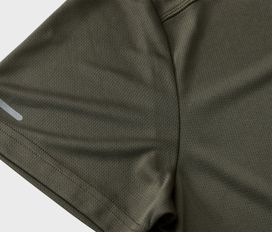 Gros plan sur la manche d'un t-shirt de sport vert olive avec une bande réfléchissante.