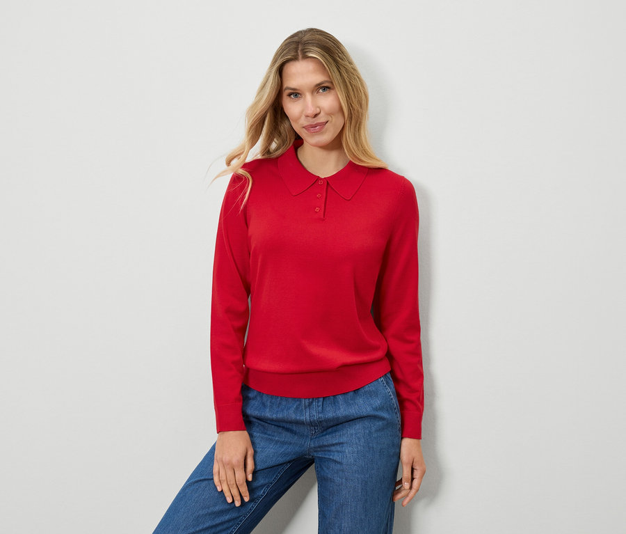 Une femme porte un pull rouge et un jean bleu.