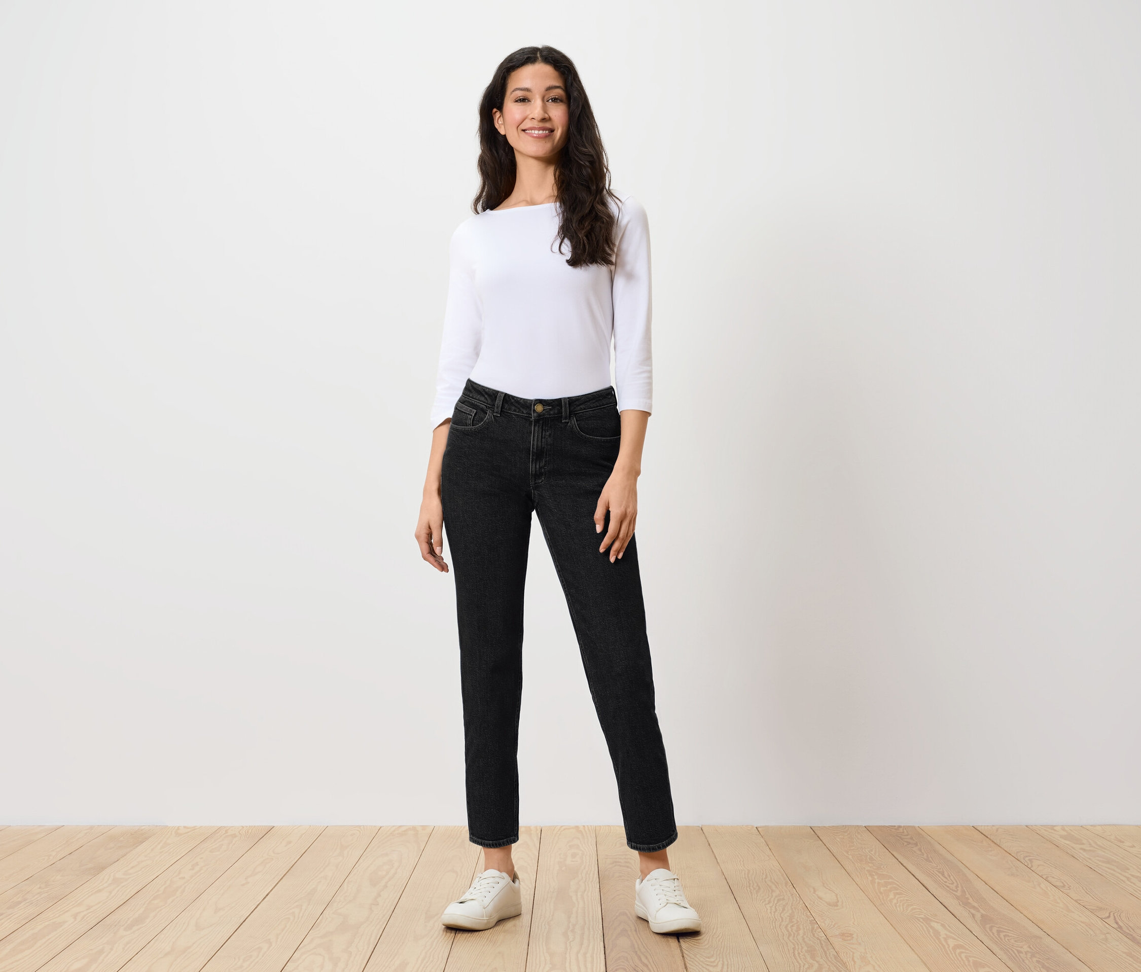 Femme debout portant un chemisier blanc et un jean moderne – Fit « Ava ».