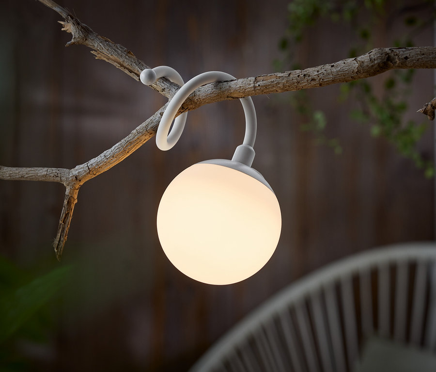 Une lampe sphérique blanche est suspendue à une branche.