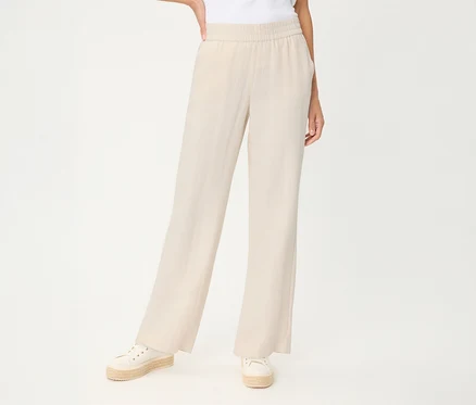 Personne en pantalon en lin Olsen beige clair à jambes larges et taille élastique, avec espadrilles blanches.
