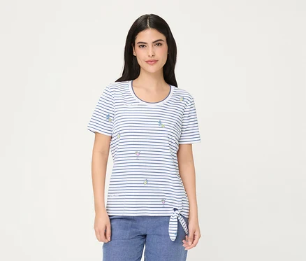 Femme portant un T-shirt Olsen, un haut à manches courtes rayé blanc et bleu avec de petits motifs de verres à cocktail et de tranches de citron, noué sur la hanche gauche, associé à un pantalon bleu.
