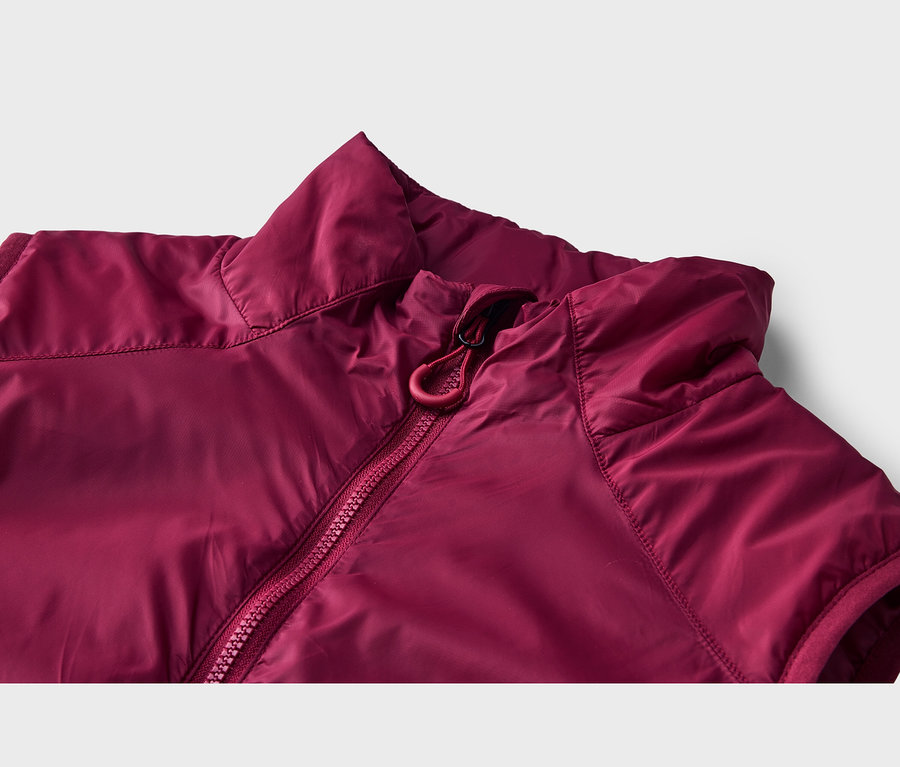 Gros plan d'une veste sans manches bordeaux, avec un col montant et une fermeture éclair rouge avec un tirette en cordon.