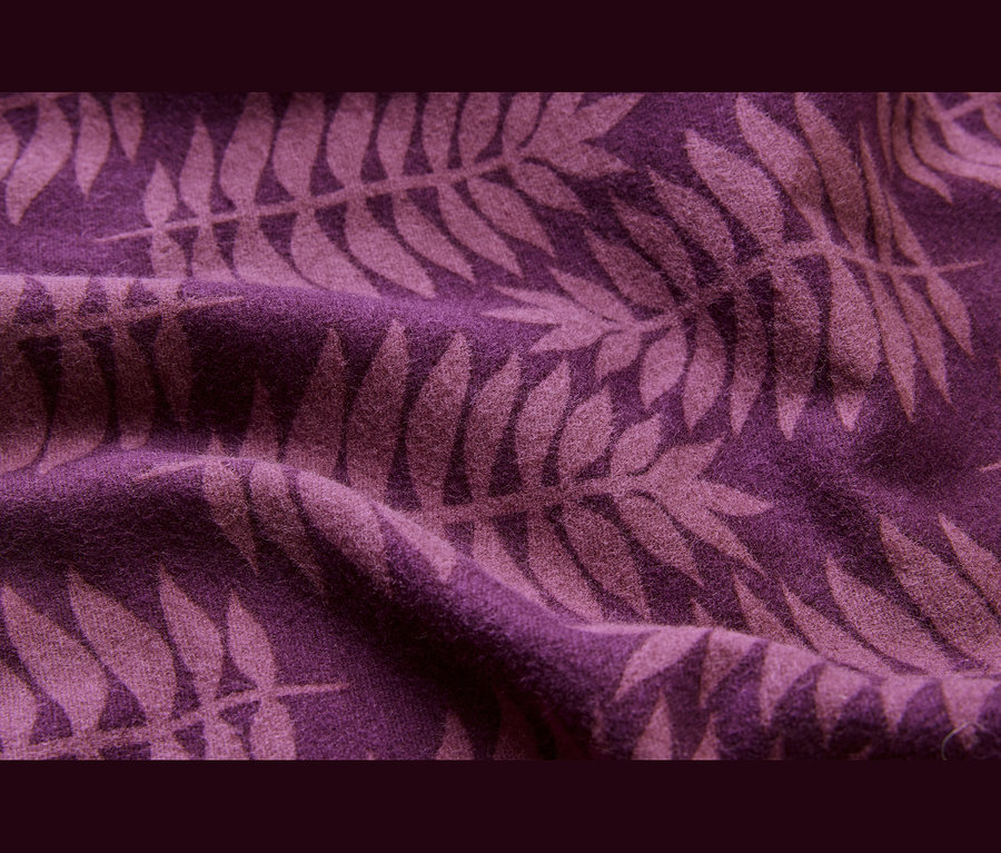 Tissu violet foncé avec des motifs de feuilles de fougère plus clairs et des plis.