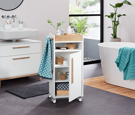 Dans une salle de bain, on trouve une armoire sous-lavabo blanche «Eklund» à deux tiroirs, un organisateur, un distributeur de savon liquide, un linge de bain en tissu éponge, 2 linges de toilette en jacquard, 2 linges de toilette en tissu éponge (anthracite), 2 boîtes en bambou, 2 pierres décoratives à LED et un chariot d’appoint pour salle de bains «Eklund».