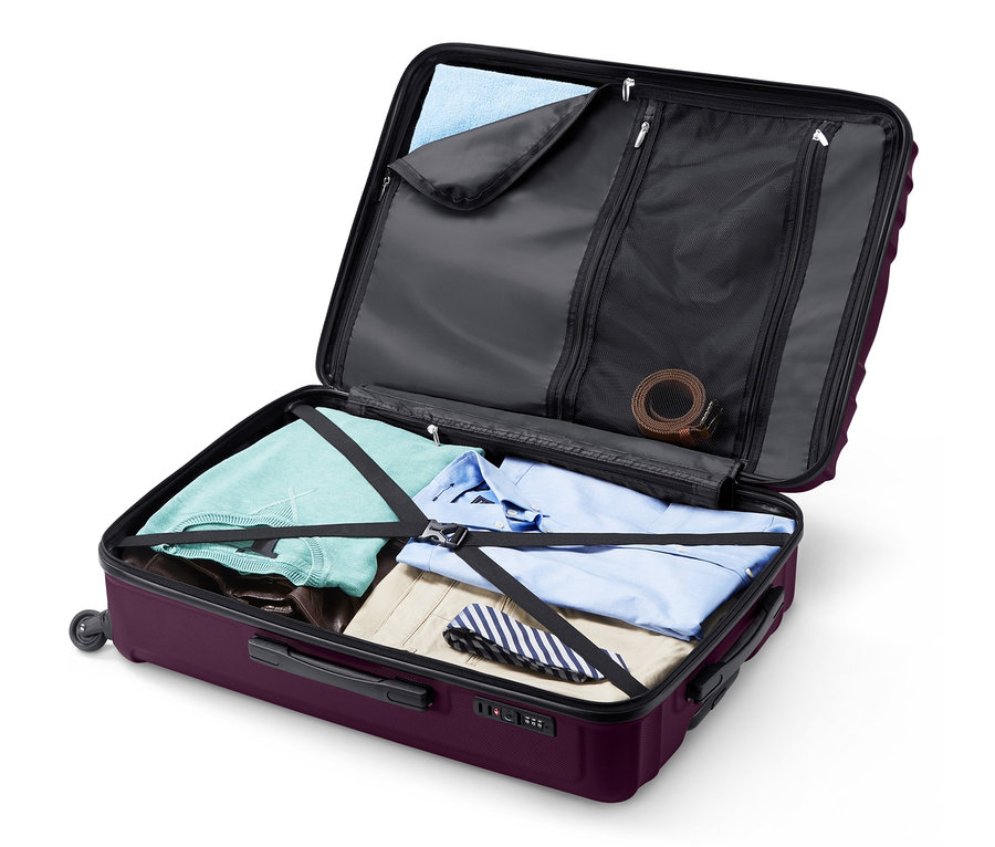 Valise rigide ouverte de grande taille et de couleur violette remplie de vêtements.